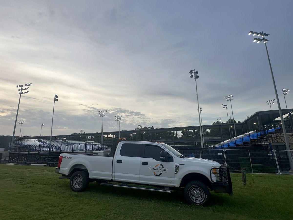 ClearSpan Infrastructure truck parked beside temporary fence panels outside a stadium at dusk